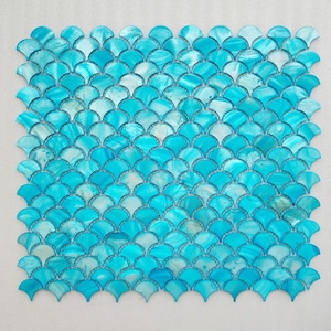 Op de afbeelding: Een vierkante mozaïektegelplaat met een herhalend waaiervormig patroon. De tegels zijn een mix van blauw en wit, waardoor een glinsterend, aquatisch effect ontstaat. Het ontwerp doet denken aan zeemeerminstaarten.