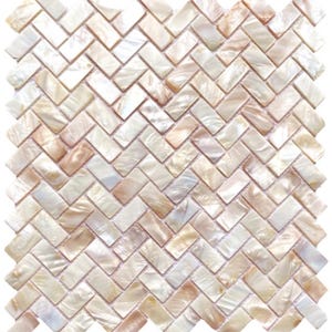 May include: A square mosaic tile sheet with a herringbone pattern. The tiles are rectangular, with a pearlescent finish in white, cream, and light brown. The tiles are arranged in a zigzag design, creating a textured surface, suitable for interior design.