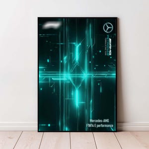 Puede incluir: Un póster enmarcado con un diseño abstracto en verde azulado y negro con líneas brillantes y formas geométricas. El logotipo y el texto de Mercedes-AMG son visibles en la esquina superior derecha. El texto "Mercedes-AMG F1W14 E performance" está en la parte inferior.