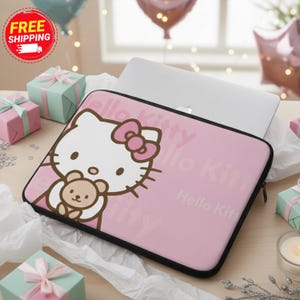 May include: Pink laptop sleeve featuring a Hello Kitty design with a bow and a teddy bear. The sleeve has a black zipper and the words "Hello Kitty" printed on the pink background. A laptop is inside the sleeve.