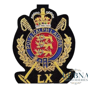Könnte beinhalten: Gestickter Aufnäher mit schwarzem Hintergrund, mit goldener Krone, gekreuzten goldenen Schwertern und den Worten "POLO RALPH LAUREN" in einem blauen Kreis. Die Mitte hat einen roten Kreis mit drei goldenen Löwen. Die Buchstaben "LX" stehen unten.