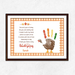 May include: Thanksgiving-themed artwork in a brown frame. The artwork features a handprint turkey with colorful fingerprints and the text "Happy Thanksgiving Day". The background has an orange and white checkered pattern.