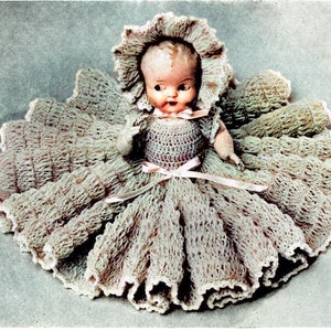 May include: A crocheted doll dress with a ruffled skirt and a matching bonnet. The dress is a light beige color and the bonnet has a white lace trim.