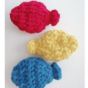 May include: Three crocheted fish toys in different colors: red, yellow, and blue. The fish are made with a textured yarn and have a slightly rounded shape.