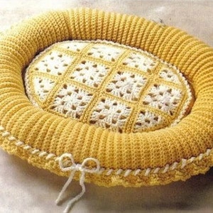 May include: A yellow crocheted pet bed with a white crocheted centre. The bed has a white ribbon tied around it.