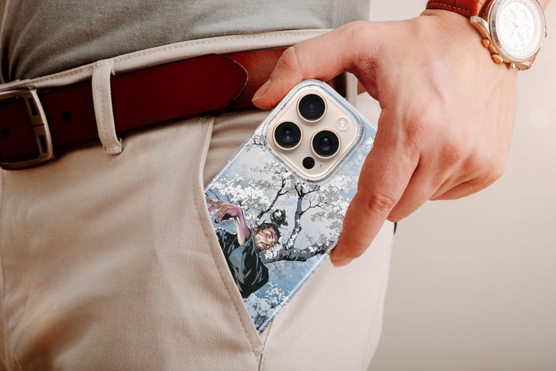K&ouml;nnte beinhalten: Eine transparente Handyh&uuml;lle mit einer detaillierten Illustration einer Figur in einem Baum mit wei&szlig;en Bl&uuml;ten. Die H&uuml;lle wird in einer Tasche gehalten, mit einem braunen G&uuml;rtel und einer Uhr sichtbar.