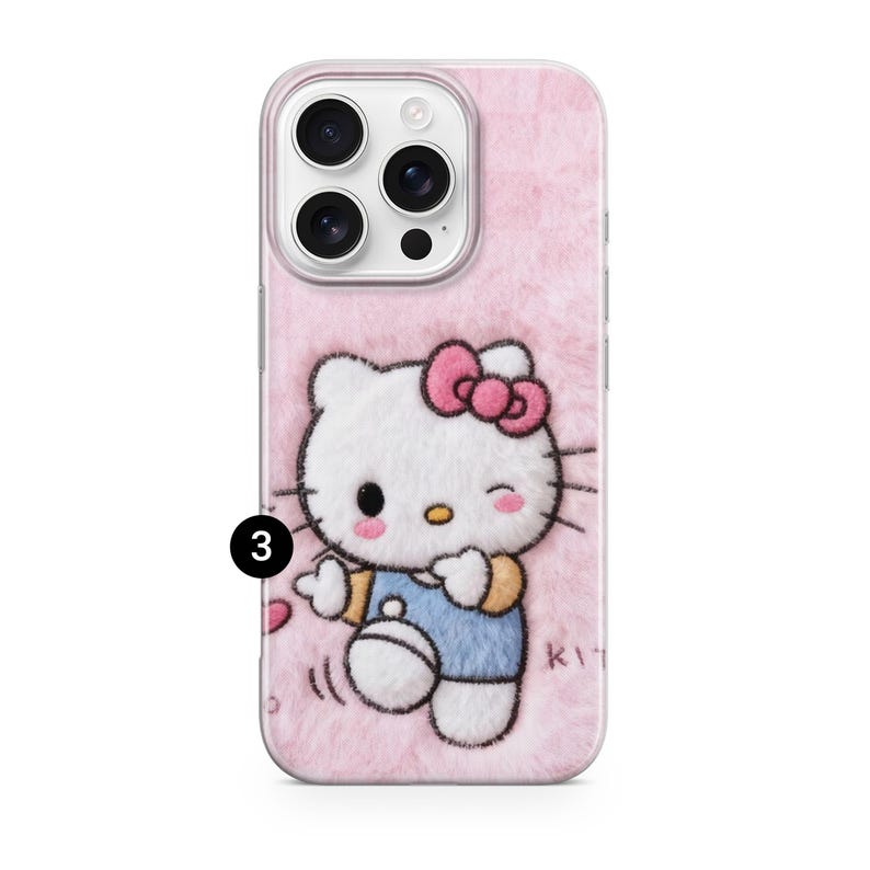 May include: Pink phone case with a fuzzy texture and a Hello Kitty design. The design features a white cat with a pink bow, wearing a blue outfit, and winking. The case has a camera cutout.