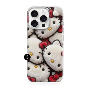 May include: A clear phone case featuring a repeating pattern of white, plush Hello Kitty faces with red bows and black stitched details. The phone case has a clear border and a camera cutout.