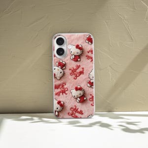 May include: A phone case featuring a repeating pattern of Hello Kitty characters in red and white on a pink, textured background. The words "Hello Kitty" are also printed in red. The case is made of clear plastic.