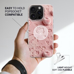 May include: Pink phone case with embossed Hello Kitty design, apples, and other shapes. The case is shown being held in a hand. Text on the case reads "EASY TO HOLD POPSOCKET COMPATIBLE" and "LIGHT WEIGHT SOFT AND FLEXIBLE".