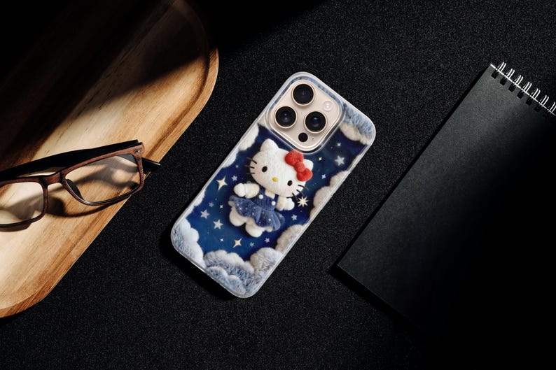 May include: A phone case featuring a Hello Kitty design. The case has a blue background with white clouds and stars. Hello Kitty is wearing a blue dress and a red bow. The case is on a black surface.