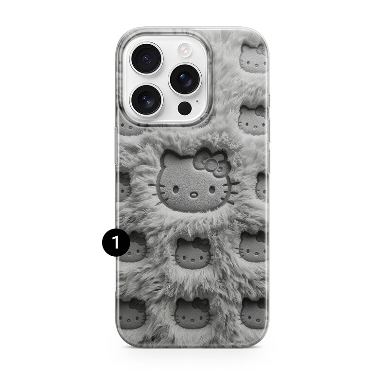 May include: A gray phone case with a fuzzy texture and embossed Hello Kitty faces. The case has a large Hello Kitty face in the center and smaller faces scattered across the surface. The camera lenses are visible at the top.