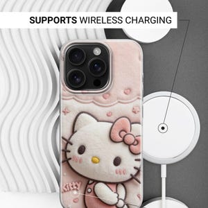 May include: A pink phone case featuring a 3D design of Hello Kitty with a bow. The case has a clear border and the text "SUPPORTS WIRELESS CHARGING" and "SIDES ARE NOT PRINTED".