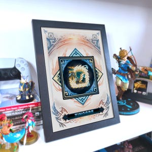 以下が含まれることがあります： モンスターハンターのビデオゲームシリーズに登場するモンスターの、様式化されたイラストが描かれた額装されたアートワーク。 アートワークは黒いフレームで、下部に「ZINOGRE」という名前が含まれています。 アートワークは、他のフィギュアと一緒に白い棚に展示されています。