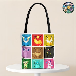 May include: White tote bag featuring nine colorful cartoon characters in square panels. The bag has a black handle and is sitting on a white table. The characters are from the Pokemon franchise.