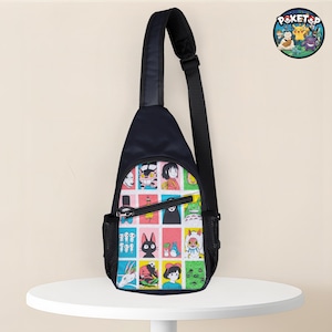 May include: A black sling bag with a colorful patchwork design featuring anime characters. The bag has a single adjustable strap, a zippered main compartment, and a small mesh side pocket. A circular logo with cartoon characters is visible.