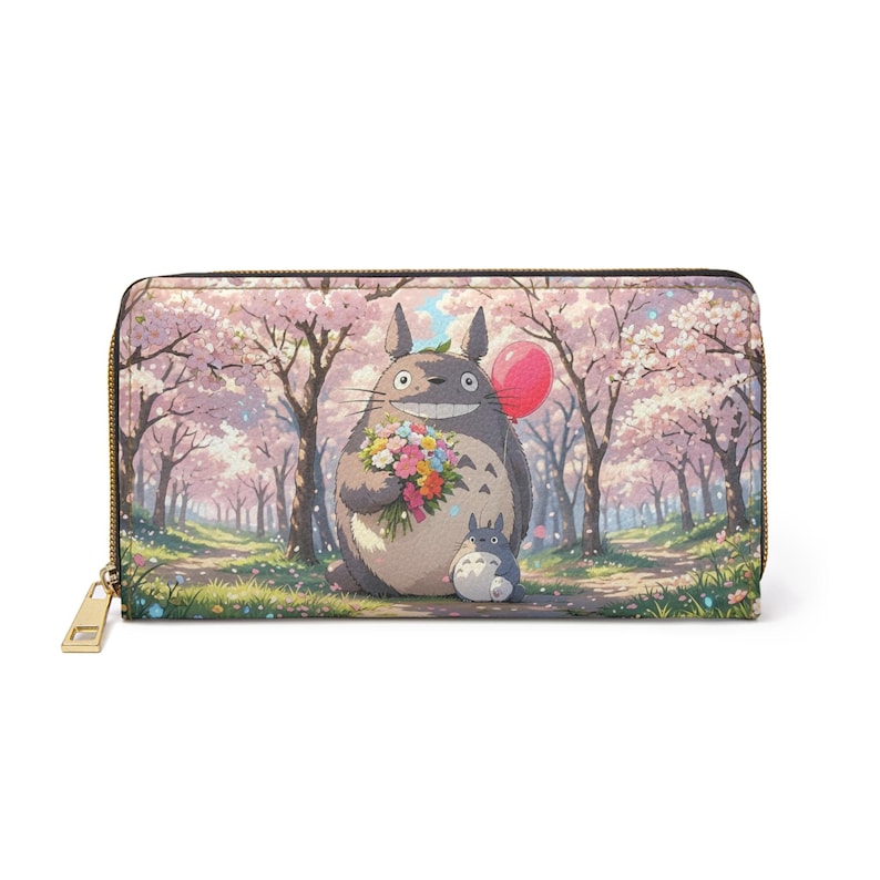 May include: A zip-around wallet with a colourful illustration of Totoro in a cherry blossom scene. The wallet has a gold-coloured zip and pull. The design features a large Totoro holding flowers and a balloon.