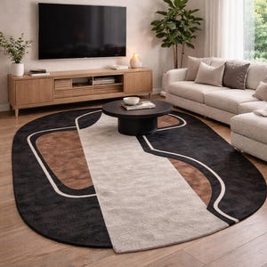 May include: An oval area rug with a modern design. The rug features a black background with brown and beige geometric shapes outlined in white. The rug is placed in a living room with a sofa, TV, and coffee table.