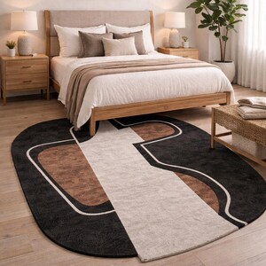 May include: An oval area rug with a modern design. The rug features a black background with geometric shapes in brown and off-white, outlined with a white border. The rug is placed in a bedroom setting.