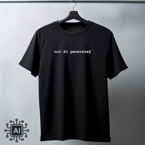 May include: Black crew neck t-shirt with the text "not AI generated" in white. The shirt is hanging on a black hanger against a gray background. A graphic of a circuit board with "AI" is in the lower left corner.