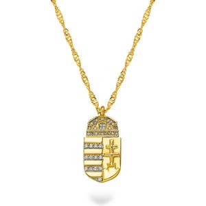 Könnte beinhalten: Eine goldfarbene Anhängerkette mit einem Schilddesign, Kronen- und Kreuzdetails. Der Anhänger ist mit klaren Kristallen verziert und hängt an einer gedrehten Kette. Die Halskette wird vor einem weißen Hintergrund präsentiert.