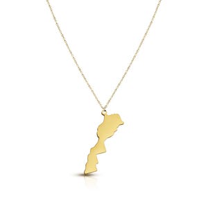 Peut inclure: Un collier doré avec un pendentif en forme de la carte du Maroc. Le pendentif est suspendu à une fine chaîne, créant un design simple et élégant. Le collier est probablement en alliage métallique.