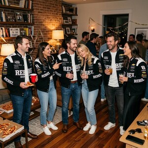 Könnte beinhalten: Eine Gruppe von Personen trägt schwarz-weiße Rennjacken mit dem Aufdruck "REBEL". Die Jacken haben verschiedene Logos und die Nummer "8". Sie sind auf einer Party versammelt, halten Getränke und Pizza.