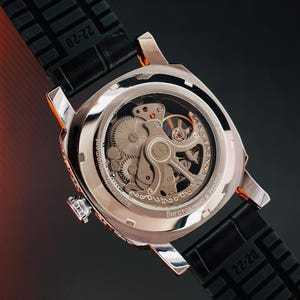 Peut inclure: Gros plan d'une montre automatique argent&eacute;e avec un bracelet en caoutchouc noir. Le dos de la montre r&eacute;v&egrave;le les m&eacute;canismes internes. Le bracelet est marqu&eacute; "22-20". La montre est &eacute;tanche &agrave; 30m.