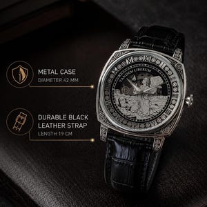 Puede incluir: Un reloj de pulsera plateado con correa de cuero negro y caja de metal de 42 mm. La esfera presenta una ilustraci&oacute;n grabada de un &aacute;ngel, el texto TANDEM LIBERUM y n&uacute;meros romanos. La correa tiene una longitud de 19 cm en total.
