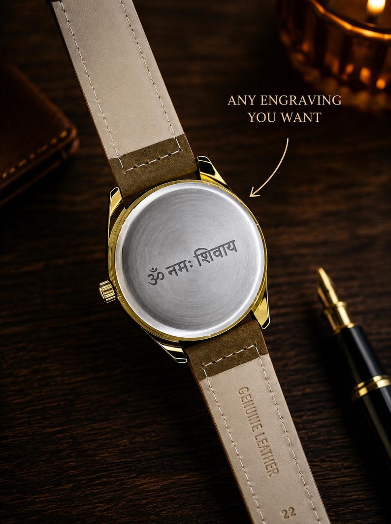 K&ouml;nnte beinhalten: Eine goldfarbene Armbanduhr mit braunem Lederarmband, auf dem "GENUINE LEATHER" und "22" steht. Die R&uuml;ckseite des Uhrengeh&auml;uses ist mit dem Sanskrit-Text "ॐ नमः शिवाय" graviert und enth&auml;lt den Text "ANY ENGRAVING YOU WANT".