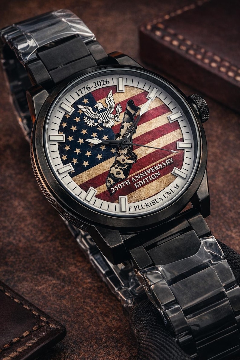 K&ouml;nnte beinhalten: Schwarze Armbanduhr mit patriotischem Design. Das Zifferblatt zeigt die amerikanische Flagge, ein Adleremblem und den Text "1776-2026" und "250th Anniversary Edition". Die Uhr hat ein schwarzes Metallarmband.
