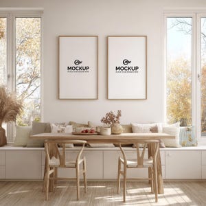May include: A bright, airy dining room with two framed mockups on the wall. A wooden table with two chairs sits in front of a built-in bench with pillows. The windows offer a view of fall foliage. The mockups have the text "MOCKUP PLACE YOUR DESIGN HERE".