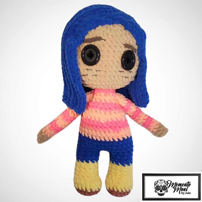 May include: A handmade crochet doll with blue hair, large black button eyes, and a striped pink and peach shirt. The doll has blue shorts and yellow shoes. The doll's arms are outstretched. The doll is a character from a movie.