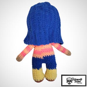 May include: A handmade plush doll with a blue head covering, pink and orange striped torso, blue pants, and yellow shoes. The doll has brown arms and feet. The doll is made of a soft, textured material. The doll is a unique, handcrafted item.