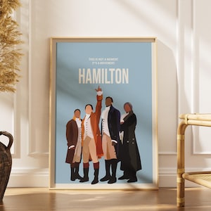 Peut inclure: Affiche encadrée avec une illustration minimaliste de quatre personnages en costumes d'époque. L'affiche a un fond bleu clair avec le mot "HAMILTON" en blanc. Le texte "THIS IS NOT A MOMENT IT'S A MOVEMENT" est au-dessus du titre.