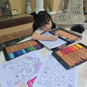 Pu&ograve; includere: Tre scatole metalliche rettangolari riempite con matite colorate assortite disposte in file, che circondano diversi fogli di carta bianca con illustrazioni a linee in bianco e nero di zucche, fantasmi e caramelle da colorare.