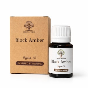 May include: A bottle of Black Amber diffuser oil with a white cap and a brown box. The box and bottle have the text "SECRET OF VEDAS" and "INSPIRED BY NATURE". The bottle is dark brown with a white label.