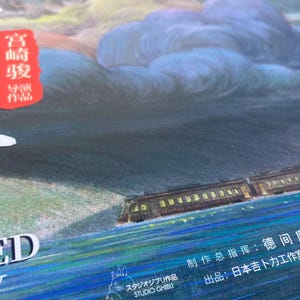 Puede incluir: Ilustraci&oacute;n colorida de un tren viajando por el agua, con un cielo nublado de fondo. La imagen incluye texto japon&eacute;s y el logotipo de Studio Ghibli. La paleta de colores incluye azules, verdes y naranjas.