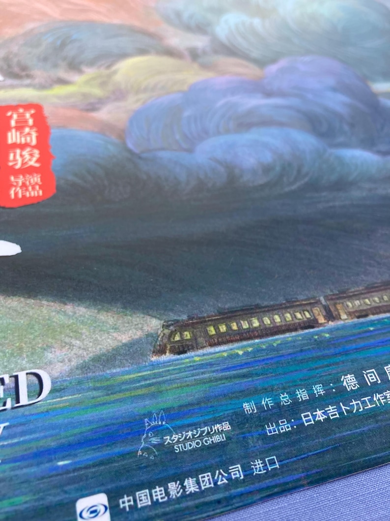 Puede incluir: Ilustraci&oacute;n colorida de un tren viajando por el agua, con un cielo nublado de fondo. La imagen incluye texto japon&eacute;s y el logotipo de Studio Ghibli. La paleta de colores incluye azules, verdes y naranjas.