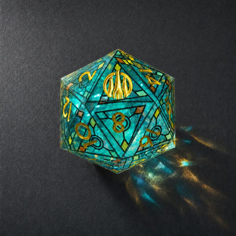 May include: A twenty-sided die featuring a translucent teal and blue stained glass pattern with gold-colored geometric lines and numbers. The die displays a central gold emblem on the top face and casts a vibrant, colorful light reflection.