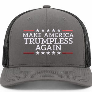 May include: Gray trucker hat with a black mesh back. The front of the hat features the text "MAKE AMERICA TRUMPLESS AGAIN" in white, with red lines and stars above and below the text. A political statement.