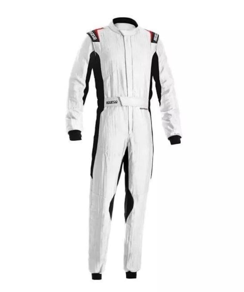 May include: White racing suit with black accents and red shoulder details. The suit features a full-length zipper, a belt, and the Sparco logo. The suit is designed for motorsports and racing.