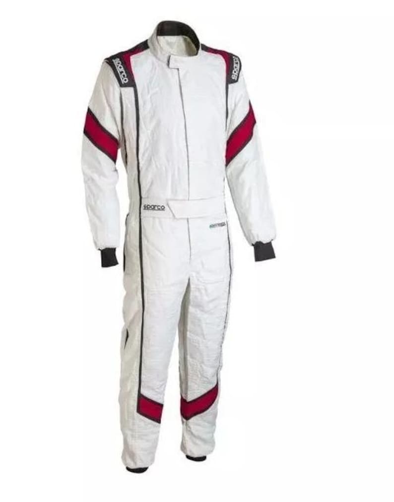 May include: White racing suit with black and red accents. The suit features a stand-up collar, long sleeves, and a front zipper. The Sparco logo is visible on the shoulders and chest. The suit has black cuffs and red stripes on the shoulders and legs.