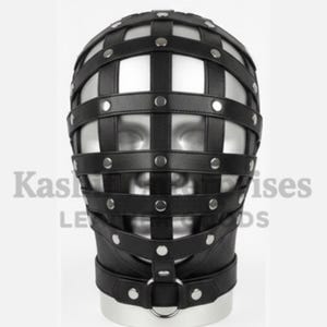 Puede incluir: M&aacute;scara facial de cuero negro con dise&ntilde;o de jaula. La m&aacute;scara presenta correas horizontales y verticales aseguradas con remaches plateados. Una correa para el cuello se conecta a un anillo met&aacute;lico.