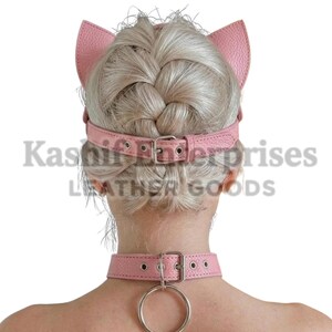Puede incluir: Diadema de orejas de gato de cuero rosa y gargantilla a juego con un anillo de metal plateado. La diadema tiene correas ajustables y cierres de hebilla. La gargantilla tambi&eacute;n tiene cierre de hebilla y un anillo de metal.