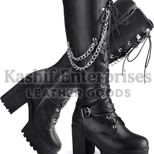 May include: A pair of black knee-high boots featuring a thick block heel, a chunky platform sole, and a lace-up front. The boots are adorned with silver-toned metal chains draped across the side and a buckle strap detail at the ankle.