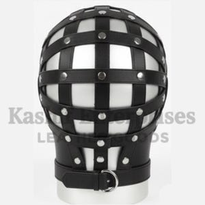 Puede incluir: Un arn&eacute;s de cabeza de cuero negro con un dise&ntilde;o en forma de jaula. El arn&eacute;s presenta correas horizontales y verticales aseguradas con remaches plateados. Una correa con una anilla en D de metal rodea la zona del cuello. El texto "Kas Leather Goods" es visible.