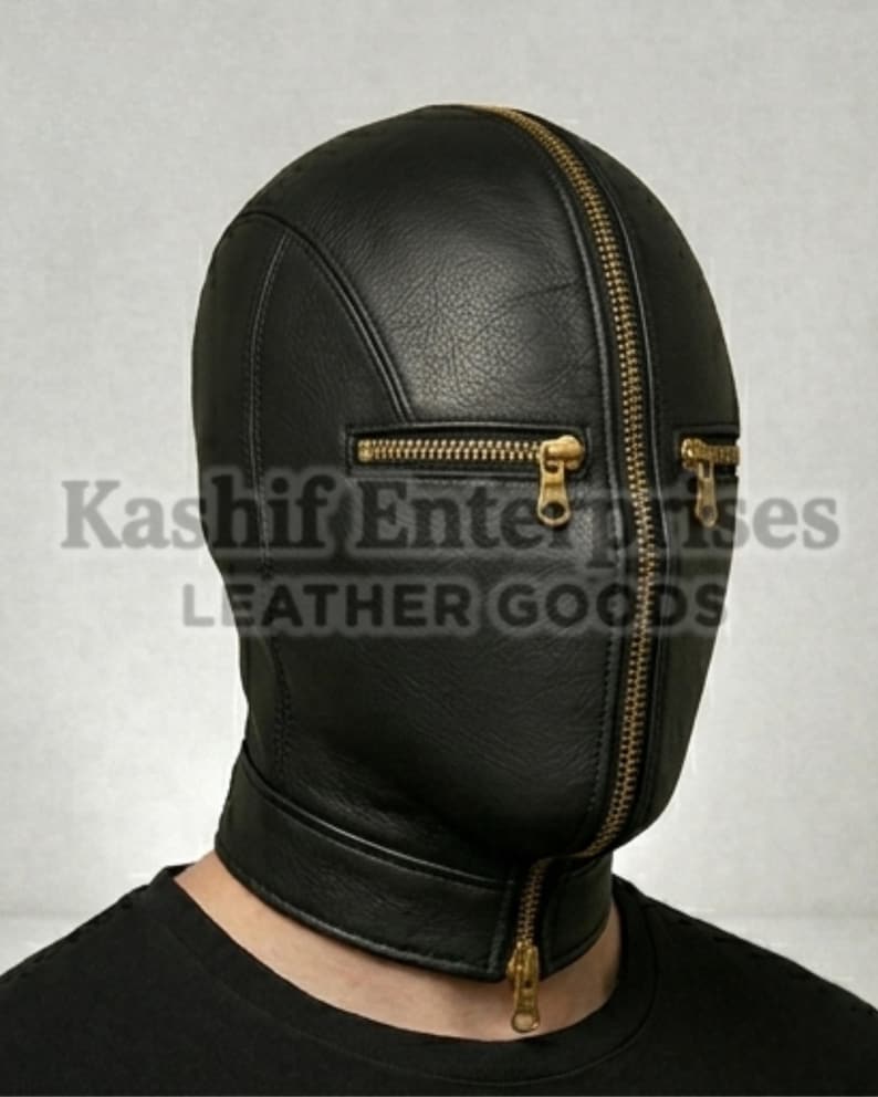 以下が含まれることがあります： 黒い革製のフード。顔全体を覆うジッパーと、目の近くにある2つの小さなジッパーが付いています。フードは頭と首を覆っています。「Kashif Enterprises LEATHER GOODS」の文字が前面に印刷されています。