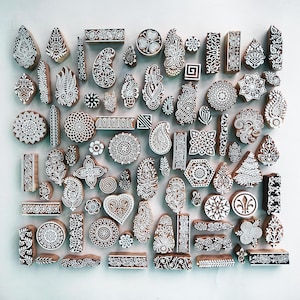 Puede incluir: Una colecci&oacute;n de bloques de impresi&oacute;n de madera con intrincados dise&ntilde;os blancos. Los bloques presentan patrones florales, geom&eacute;tricos y de cachemira, ideales para la impresi&oacute;n textil o proyectos de artesan&iacute;a. Los bloques son de varias formas y tama&ntilde;os.