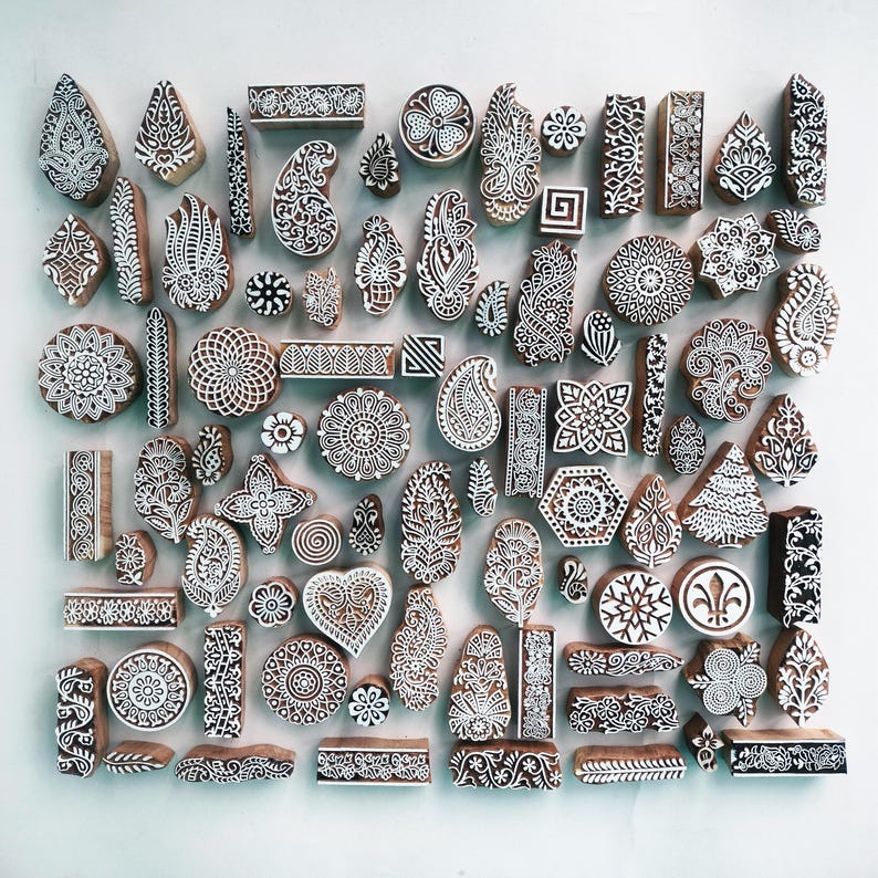Puede incluir: Una colecci&oacute;n de bloques de impresi&oacute;n de madera con intrincados dise&ntilde;os blancos. Los bloques presentan patrones florales, geom&eacute;tricos y de cachemira, ideales para la impresi&oacute;n textil o proyectos de artesan&iacute;a. Los bloques son de varias formas y tama&ntilde;os.